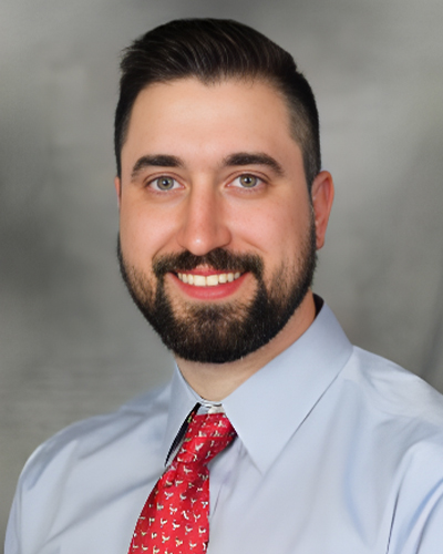 a man wearing a suit and tie smiling at the camera