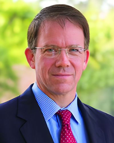 a man wearing a suit and tie smiling at the camera