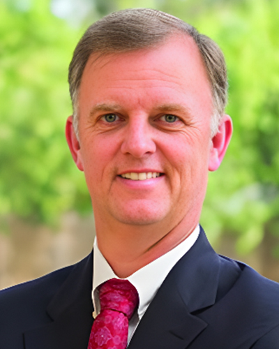 a man wearing a suit and tie smiling at the camera