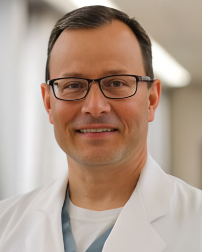 a man wearing glasses and smiling at the camera