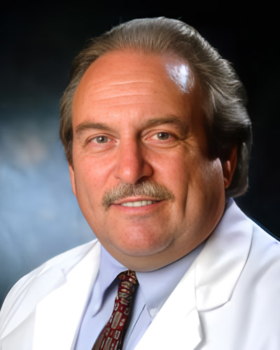 a man wearing a suit and tie smiling and looking at the camera