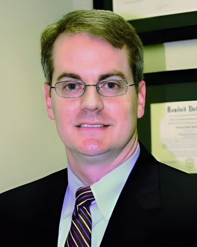 a man wearing a suit and tie smiling at the camera