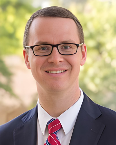 a man wearing a suit and tie smiling at the camera