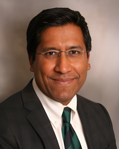 a man wearing a suit and tie smiling at the camera