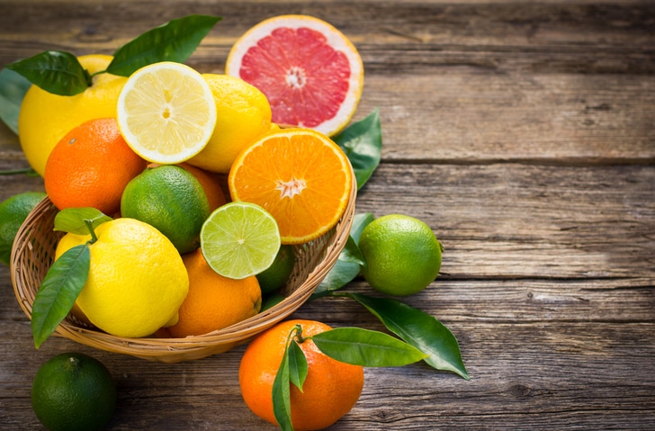 A Wicker Bowl Containing A Variety Of Immune-boosting Citrus Fruits On A Wooden Table.