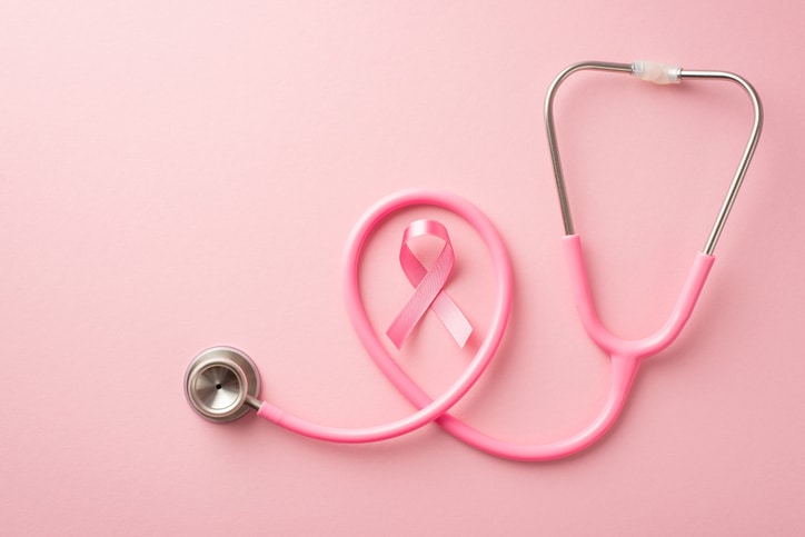 A Pink Breast Cancer Awareness Ribbon Surrounded By A Pink Stethoscope On A Light Pink Background.