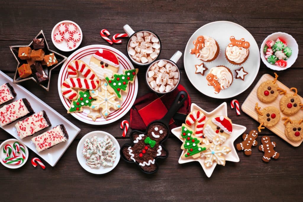 A colorful array of Christmas tree, wreath, and star cookies, some with small bows on them.