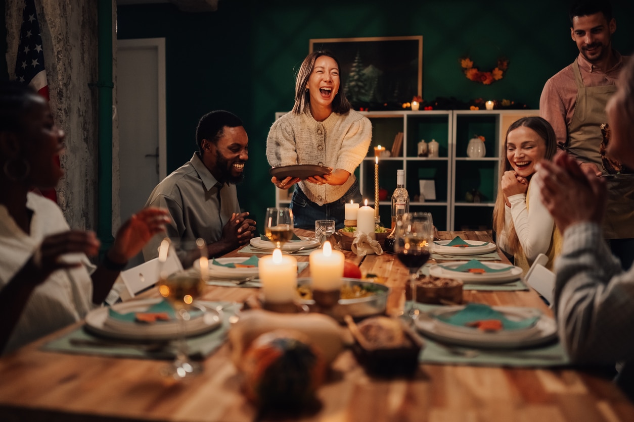 A family laughing over a holiday meal at a big dining room table