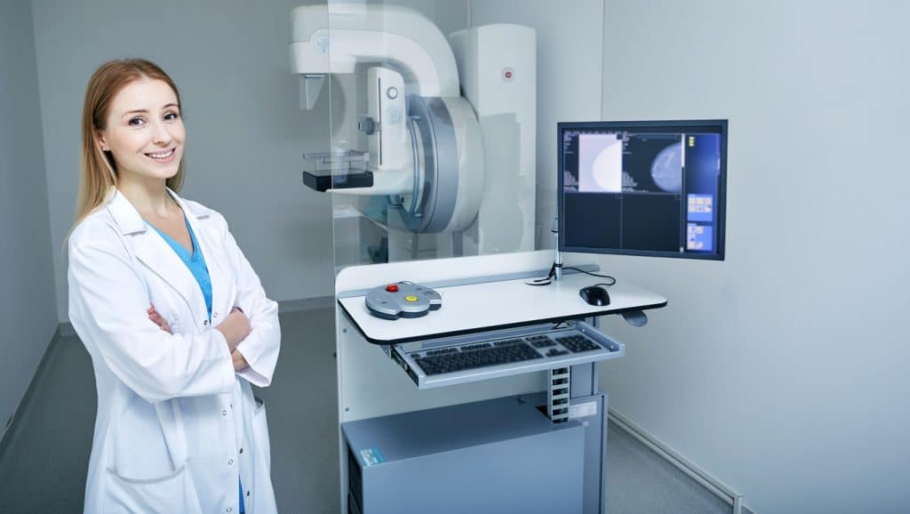 A doctor at UAB medical west standing next to a mammogram screening device 