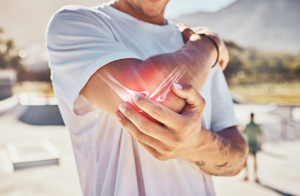 A man holding his elbow while experiencing join pain