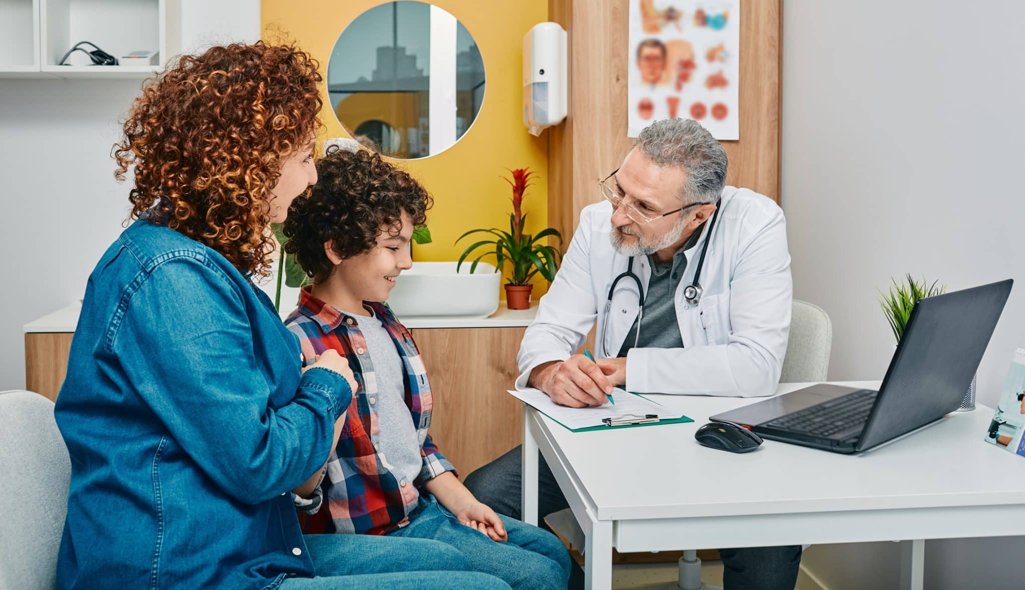 A mother and son sitting with a doctor during a back-to-school physical exam in Alabama.