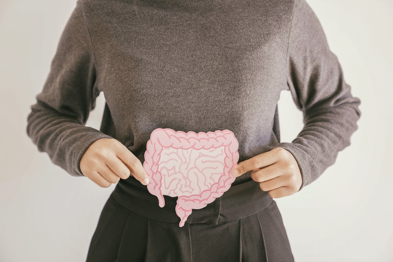 A woman holding a diagram of the intestines over her stomach, signifying changes in bowel habits.